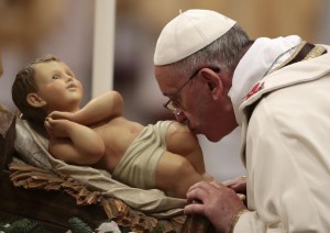 Pope Francis kisses the baby Jesus statue as he leads the Christmas night mass in the Saint Peter's Basilica at the Vatican December 24, 2013. REUTERS/Tony Gentile (VATICAN - Tags: RELIGION TPX IMAGES OF THE DAY)